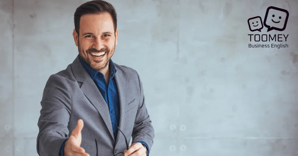 Businessman reaching out to shake hands demonstrating the concept of networking. Toomey Business English.